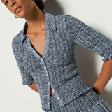 A model wearing a navy and white checkered smocked top with button closures and 3/4 sleeves.
