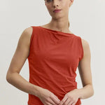 Woman wearing a red sleeveless top against a plain background