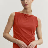 Woman wearing a red sleeveless top against a plain background