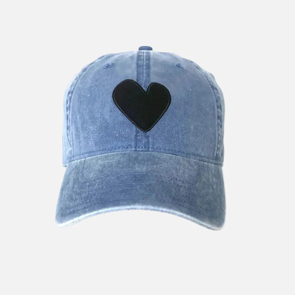 Blue denim cap with a black heart patch on a light gray background