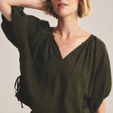 Woman wearing an olive green blouse against a plain background
