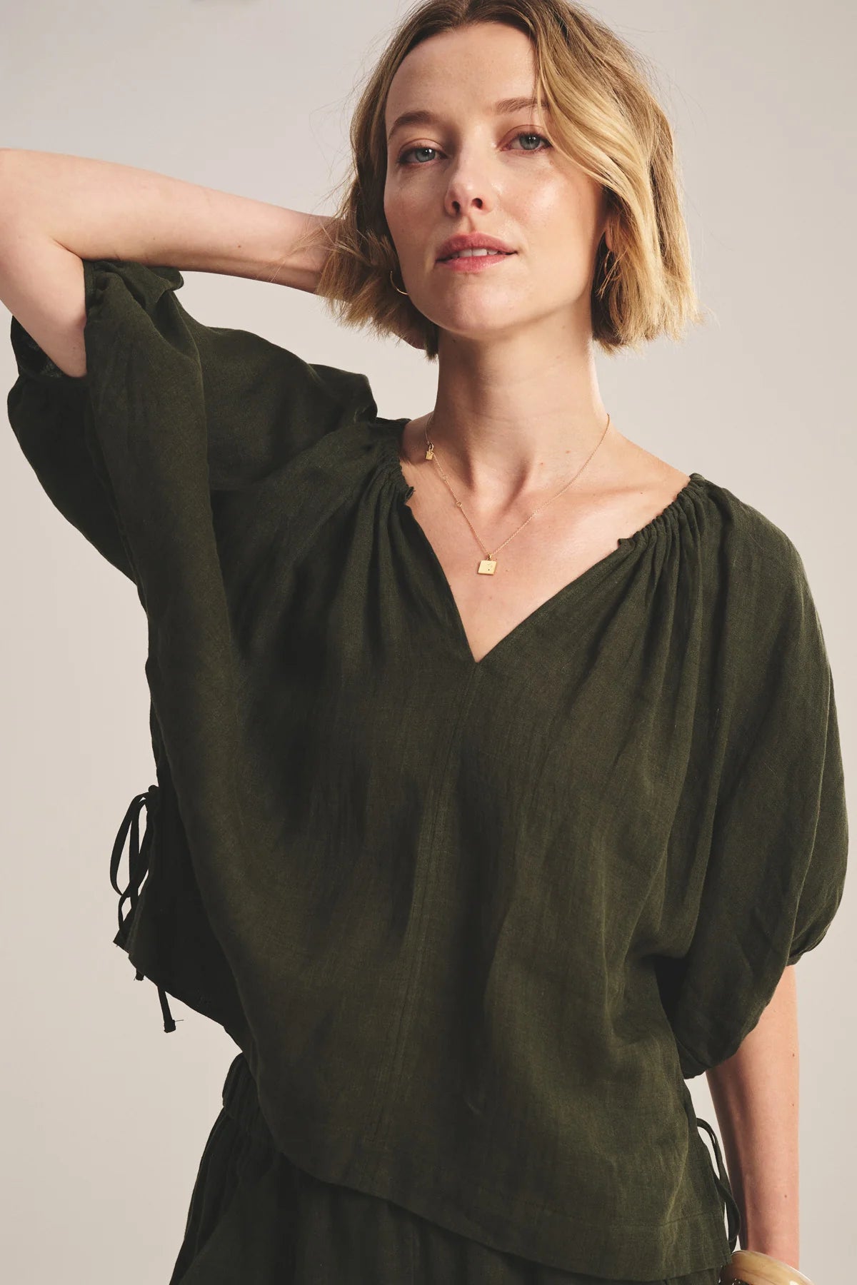 Woman wearing an olive green blouse against a plain background